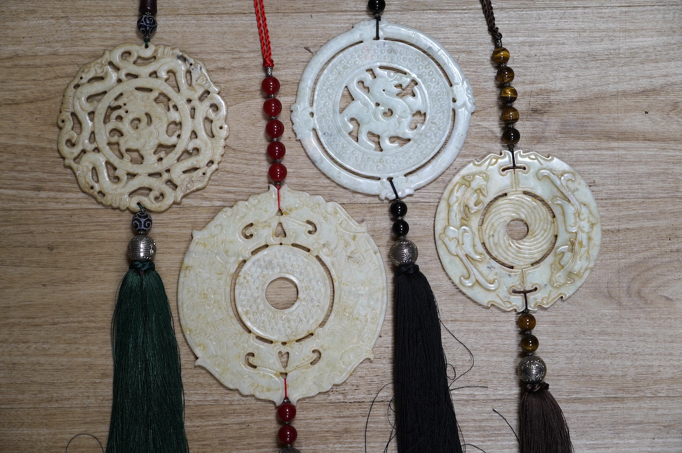 Four large Chinese carved bowenite jade discs, largest diameter 19cm, with tassel and bead wall hangings. Condition - fair to good